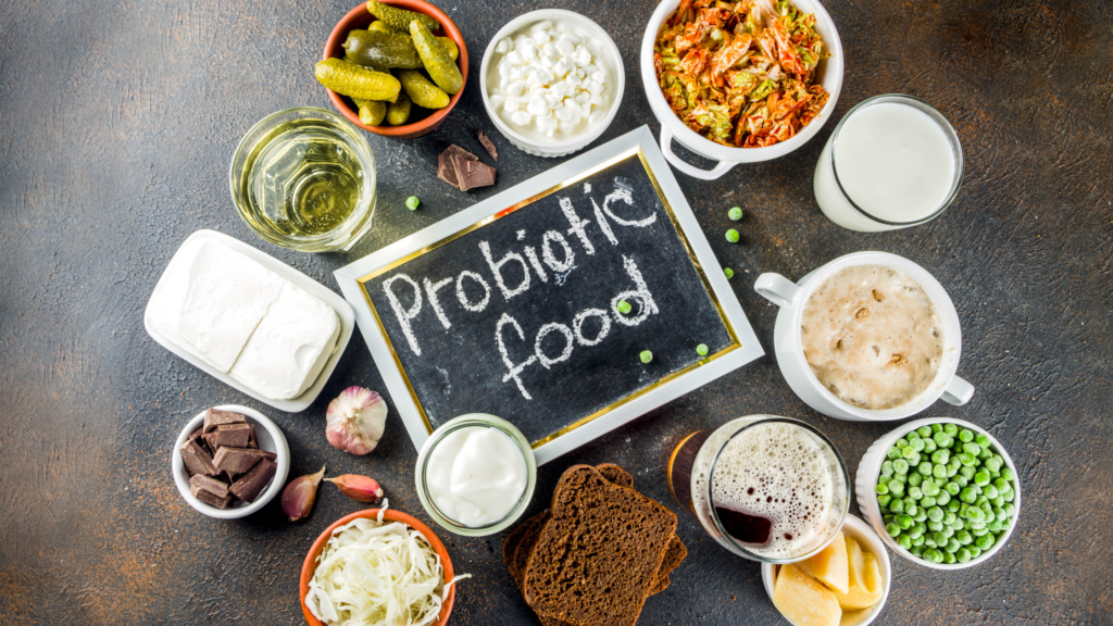 Assorted probiotic-rich foods including yogurt, kimchi, sauerkraut, and kefir, displayed on a rustic wooden table