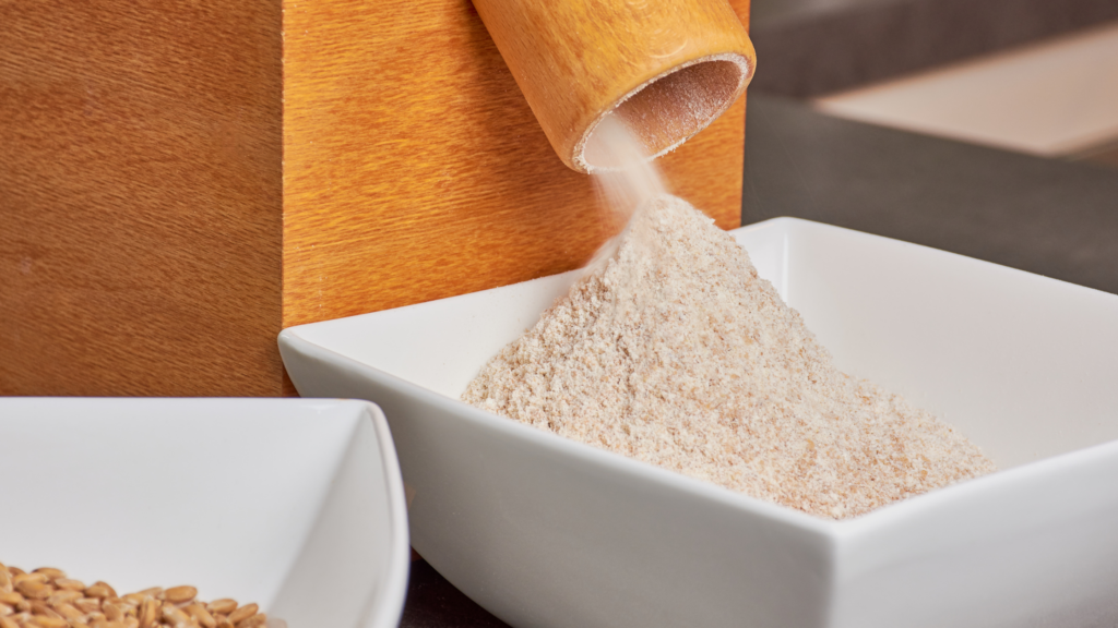 Home grain mill grinding fresh wheat berries into flour, capturing the process of milling whole grains for homemade bread.