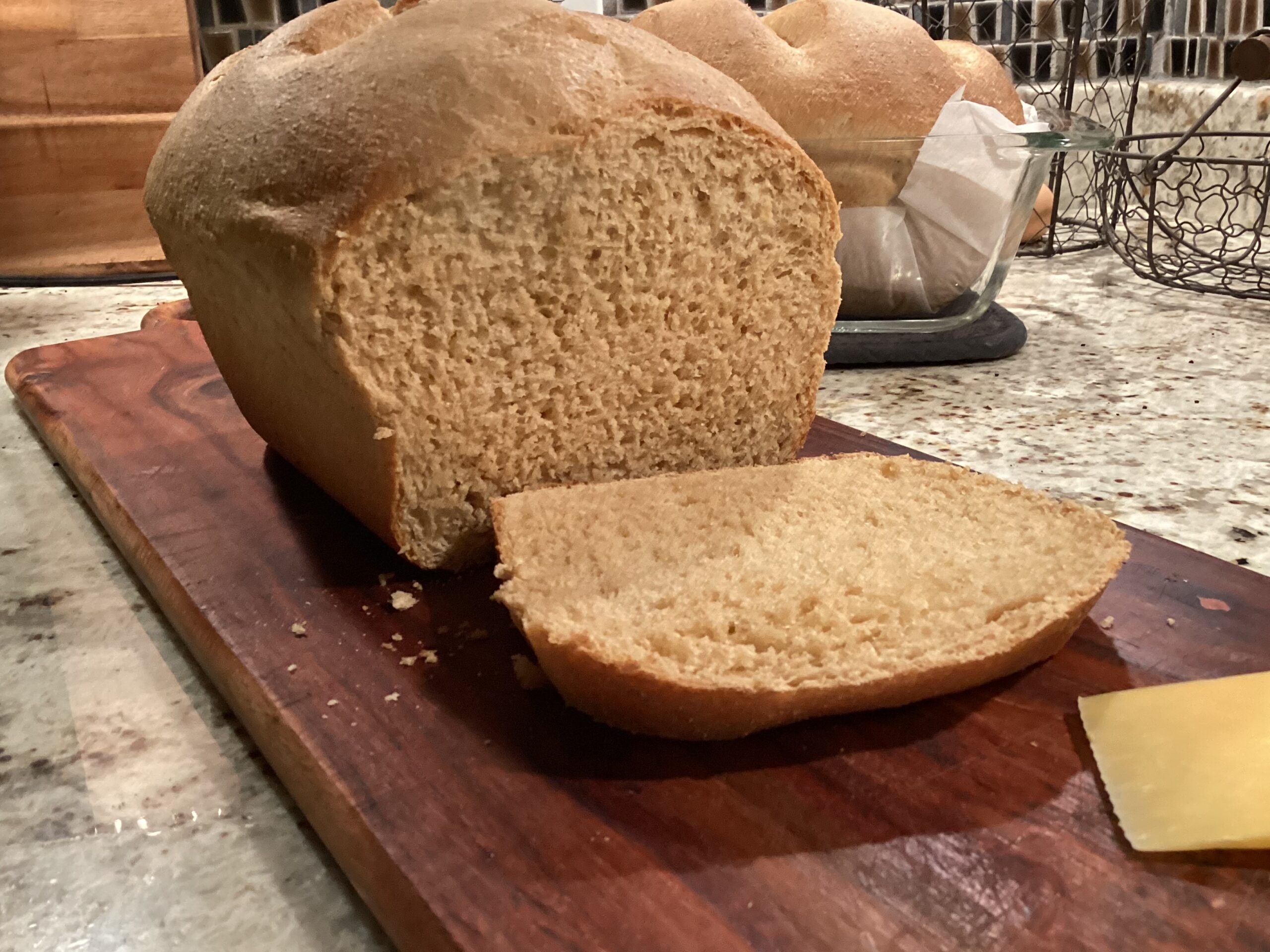 Soft, fluffy fresh milled sandwich bread on a cutting board with a slice cut