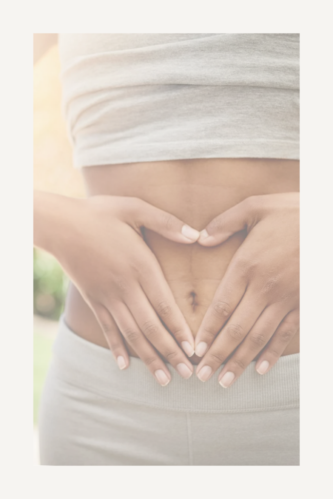 A woman forming a heart shape with her hands over her stomach, symbolizing gut health and well-being.